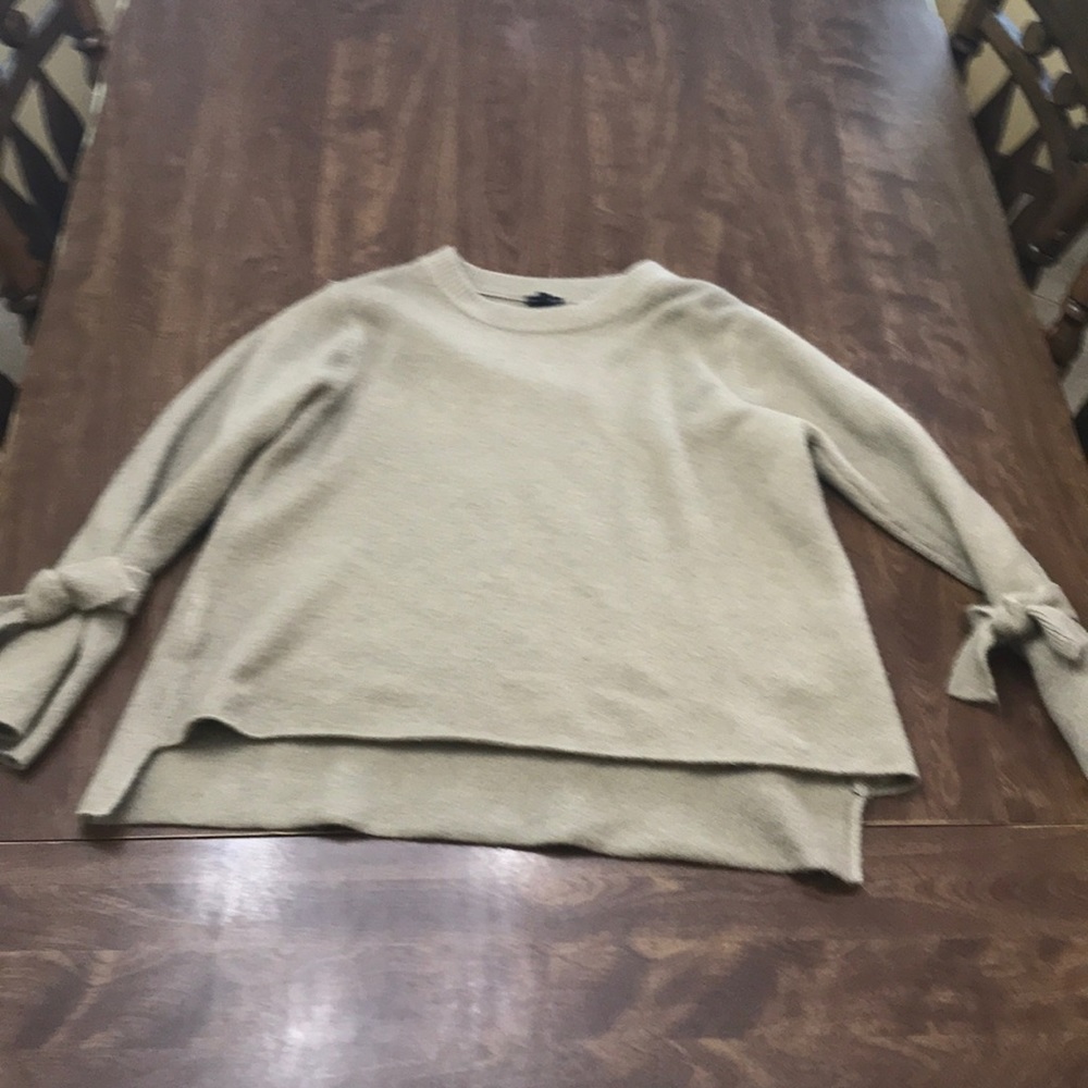 Tan sweater with fashionable knots on the sleeves.